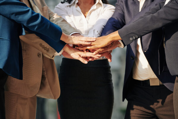 A group of corporate professionals demonstrating teamwork by joining hands.