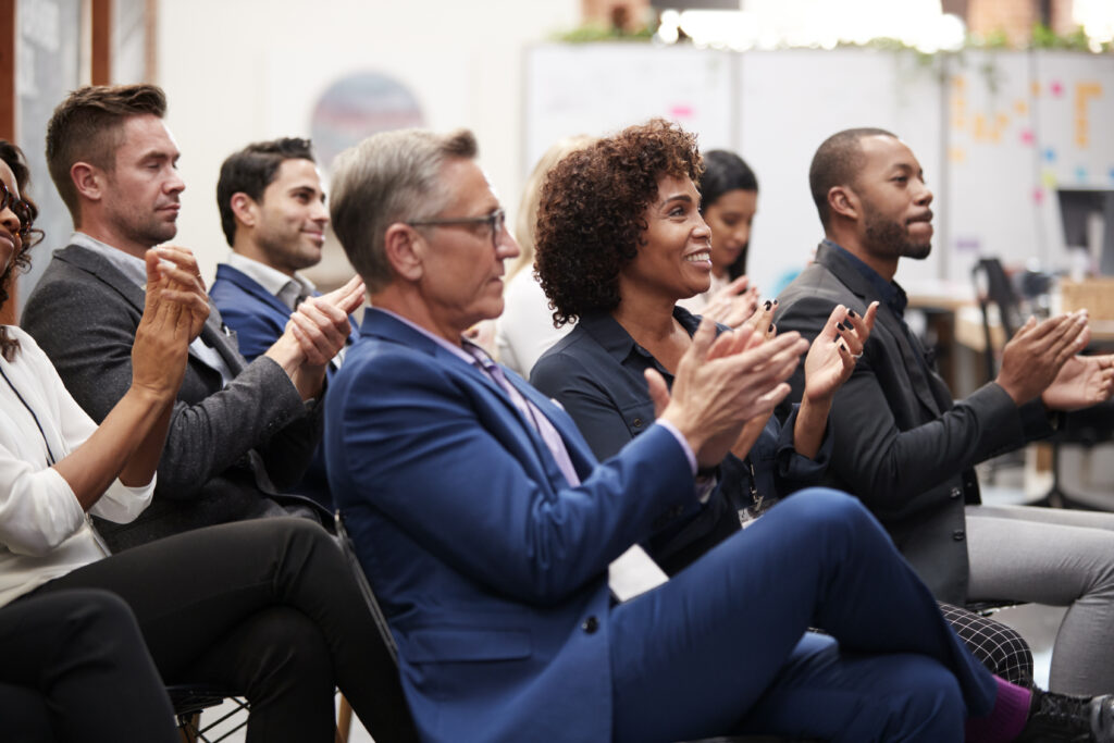 Group of business professionals smiling and applauding during a meeting.