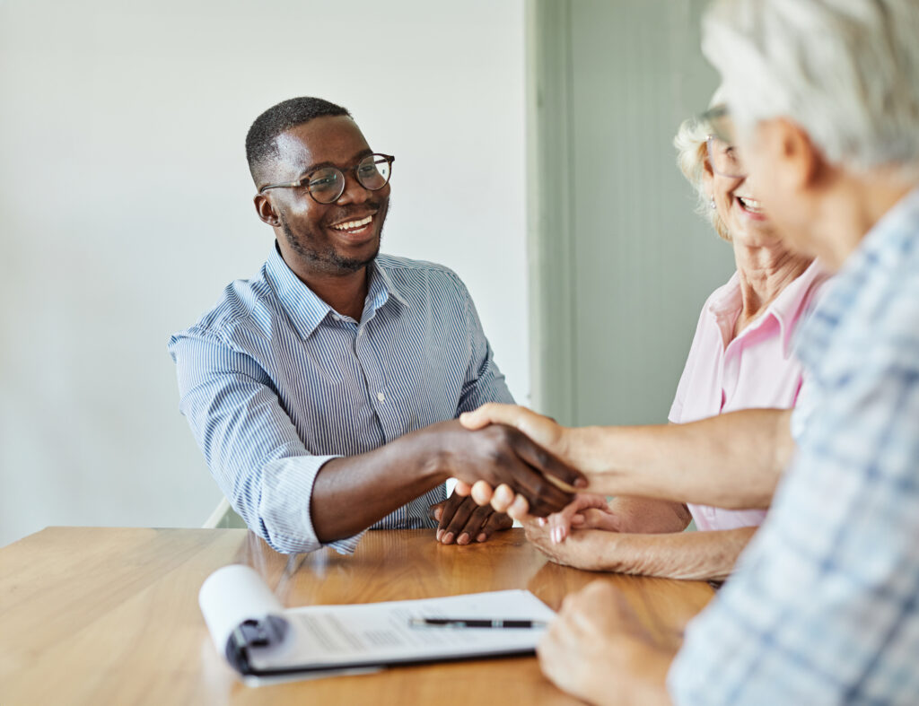 A young sales representative shaking hands with his client after having a positive meeting with them.