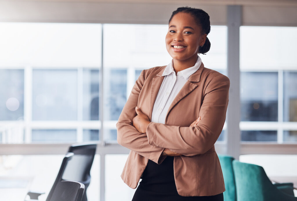 A smiling young professional standing in a modern office environment