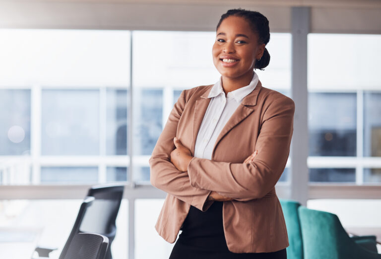A smiling young professional standing in a modern office environment