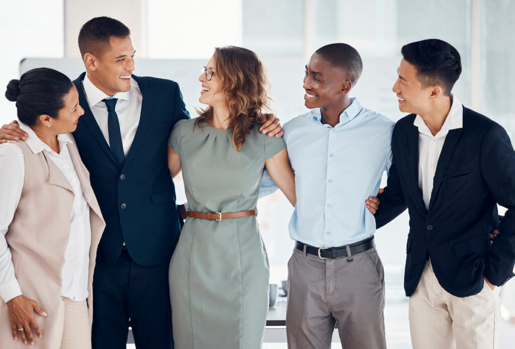 A group of five business professionals standing together in a modern corporate setting